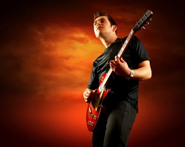 Rockový kytarista hrát na elektrickou kytaru kolem plameny ohně — Stock fotografie