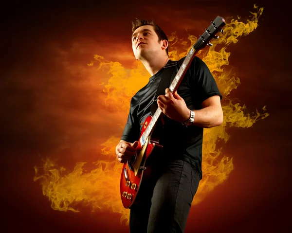 Rock guitarist play on the electric guitar around fire flames — Stock Photo, Image