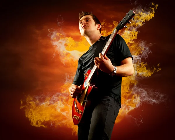 Guitarrista de rock toca en la guitarra eléctrica alrededor de llamas de fuego — Foto de Stock