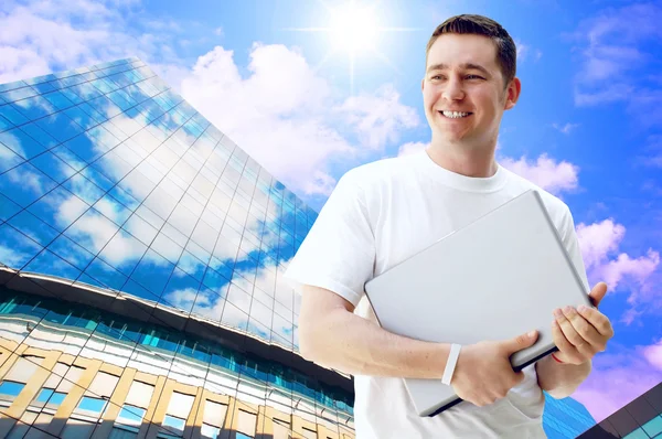 Jovem homem feliz ou estudante com laptop e telefone no negócio — Fotografia de Stock
