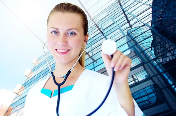 Médico sonriente con estetoscopio en los hospitales backgro — Foto de Stock