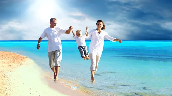 Άποψη της ευτυχισμένη νεαρή οικογένεια τη διασκέδαση στην παραλία — Φωτογραφία Αρχείου