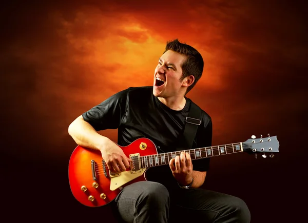 Rockgitarrist spielt auf der E-Gitarre um Feuer — Stockfoto