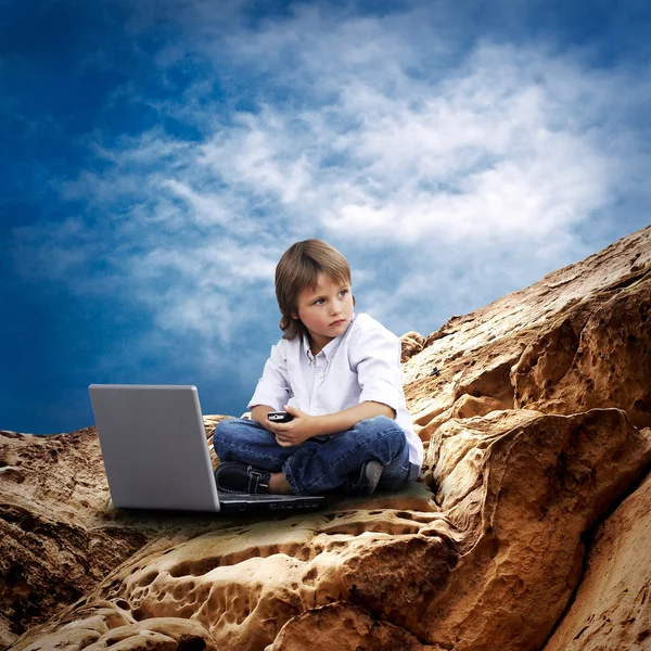 Kind mit Laptop am Brunnen unter wolkenverhangenem Himmel — Stockfoto