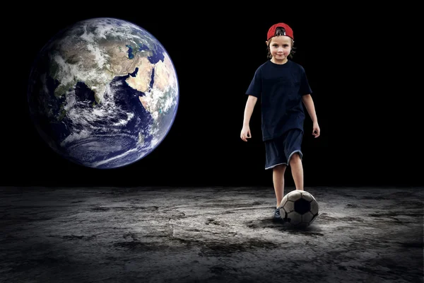 Детский футболист и гранж-мяч на тёмном фоне — стоковое фото