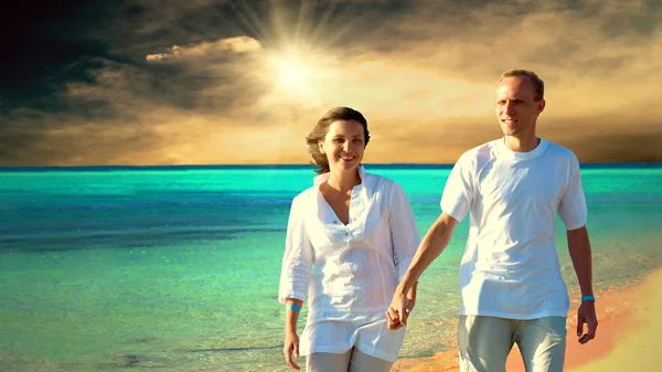 stock image View of happy young couple walking on the beach, holding hands.