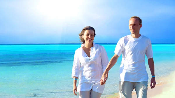 Vista de pareja joven y feliz caminando por la playa, tomados de la mano . — Foto de Stock