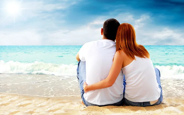 Vista mar de um casal sentado na praia . — Fotografia de Stock