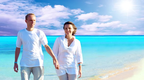 快乐对年轻夫妇在沙滩上散步手牵着手的视图. — 图库照片