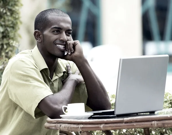 Giovane uomo felice o studente con computer portatile seduto a tavola — Foto Stock