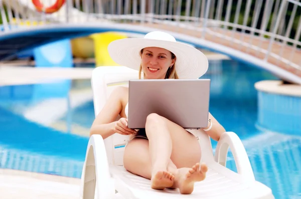 Jonge vrouwen ontspannen in de buurt van waterpool met laptop. — Stockfoto