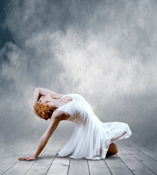 Žena tanečnice sedací pózuje na pozadí — Stock fotografie