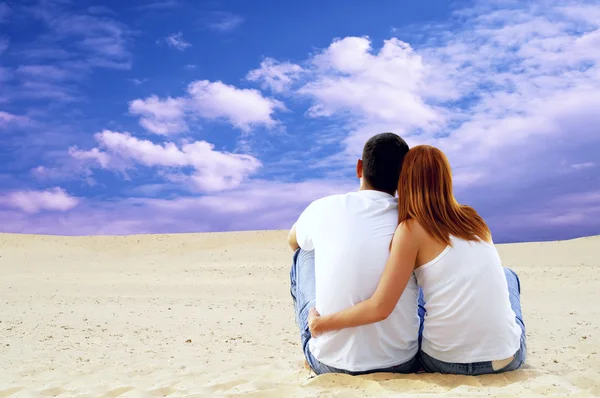 Jeune couple assis dans le désert par temps ensoleillé — Photo