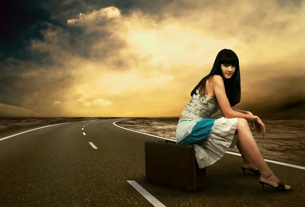 Joven mujer esperando en la carretera con su equipaje vintage — Foto de Stock