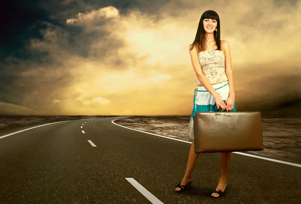 Joven mujer esperando en la carretera con su equipaje vintage — Foto de Stock