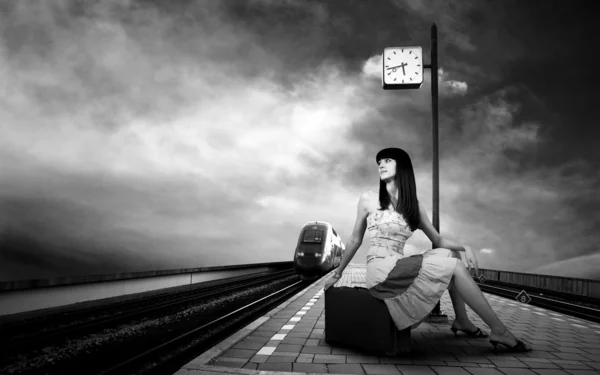 Девушка ждет поезд на платформе железнодорожного вокзала — стоковое фото