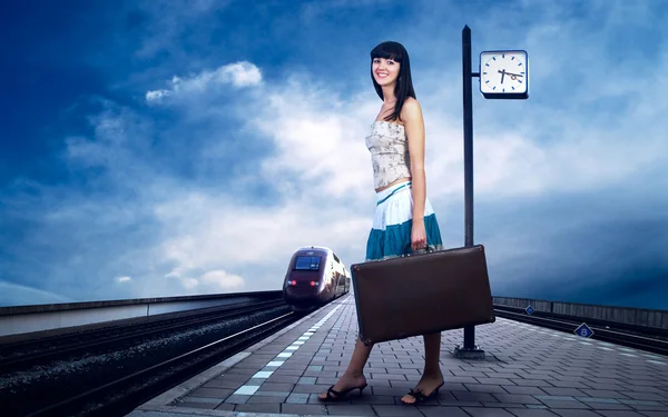 Девушка ждет поезд на платформе железнодорожного вокзала — стоковое фото