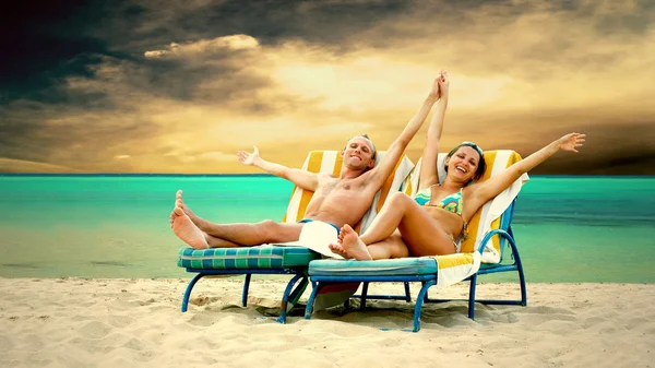Vista trasera de una pareja en una tumbona relajante en la playa —  Fotos de Stock