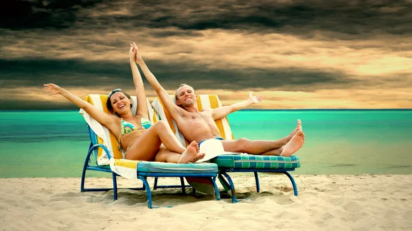 Bakifrån av ett par på en avkopplande solstol på stranden — Stockfoto