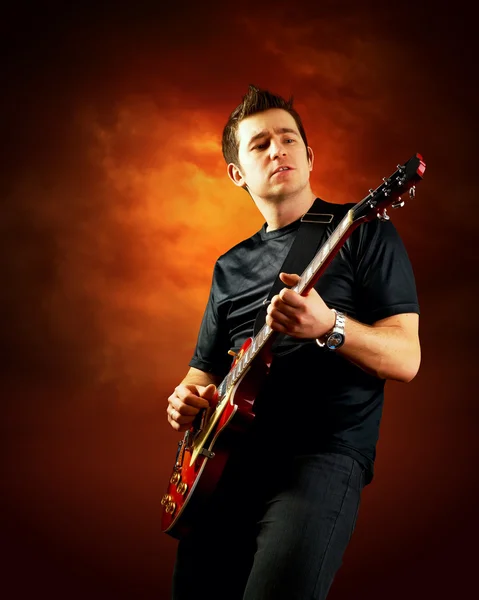 Rockový kytarista hrát na elektrickou kytaru, oranžová obloha poza — Stock fotografie