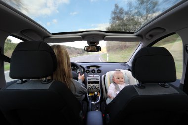 Mother driving car with her baby clipart