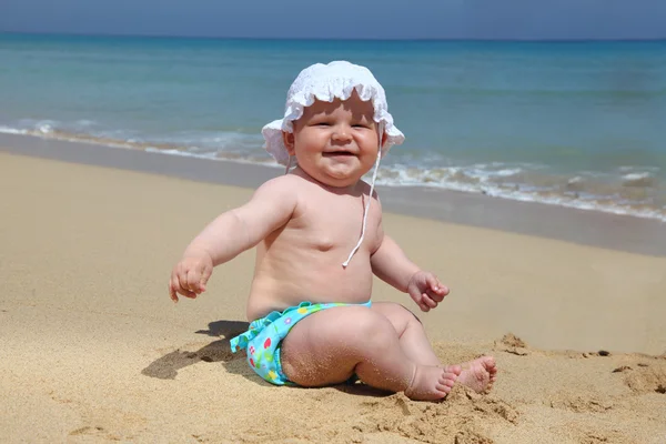 Pequena menina sentada na praia — Fotografia de Stock