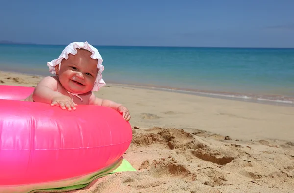 Bebê feliz em um anel rosa na praia tropical — Fotografia de Stock