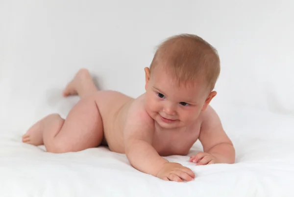 かわいい赤ちゃんのベッドで横になっていると笑みを浮かべて — ストック写真