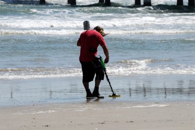 Man using metal detector on beach clipart