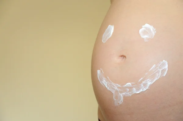 微笑的脸在怀孕的肚子上画 — 图库照片