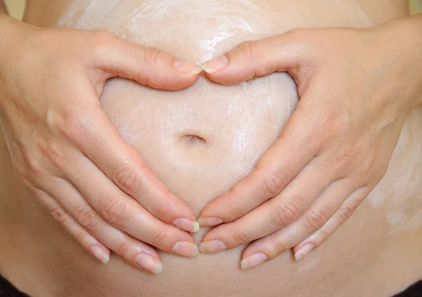 Mãos formando lareira na barriga grávida — Fotografia de Stock