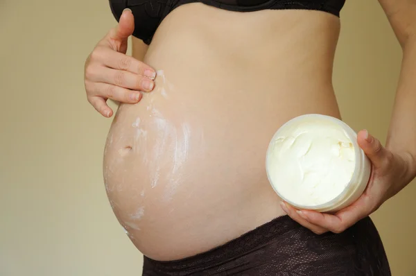 Zwangere vrouw toepassing moisturizer — Stockfoto