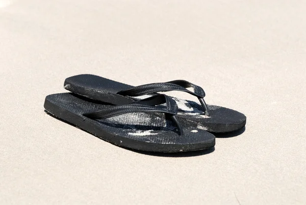 Black flip-flops on the beach — Stock Photo, Image