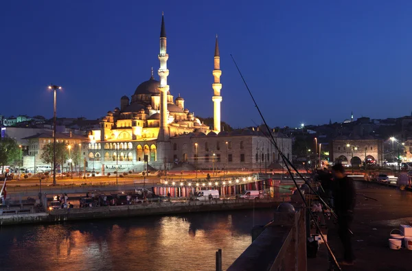 Pescatori sul Ponte di Galata e la Nuova Moschea (Yeni Camii) illuminati — Foto Stock