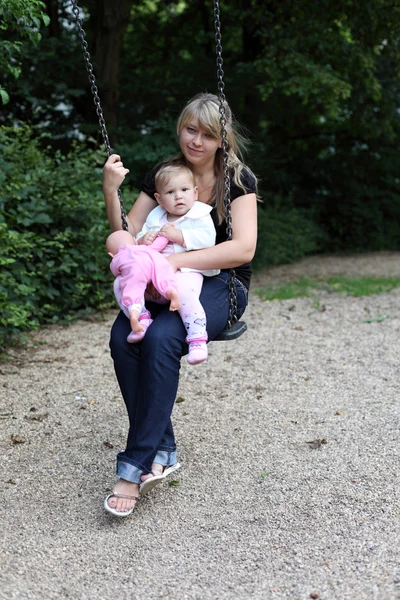 Young mother with daugther on swing — Stock Photo, Image