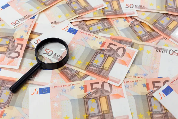Fifty euro banknotes and a magnifying glass — Stock Photo, Image