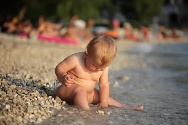 Meisje van de baby spelen met kiezels op het Adriatische strand in Kroatië — Stockfoto
