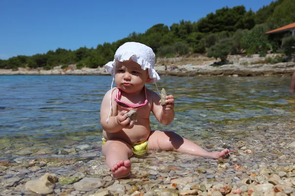 Meisje van de baby spelen met kiezels op het Adriatische strand in Kroatië — Stockfoto