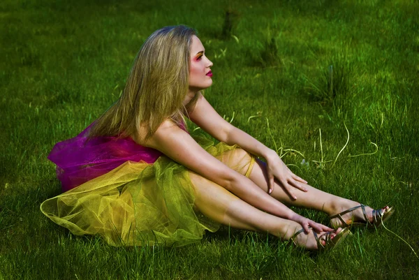 快乐的年轻女人坐在草地上 — 图库照片