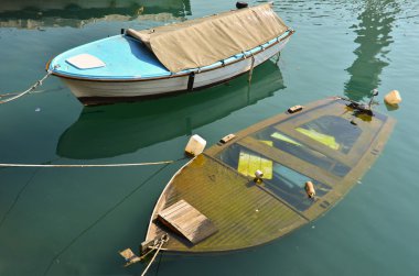 Two boats on berth, one is sinking clipart