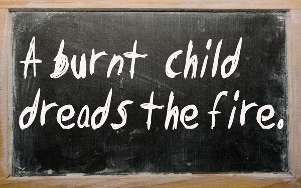 "A burnt child dreads the fire" written on a blackboard