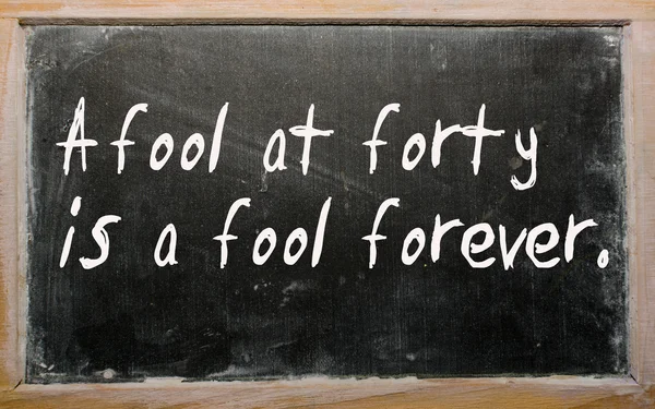 "一个四十岁的傻瓜永远是傻瓜"写在黑板上 — 图库照片