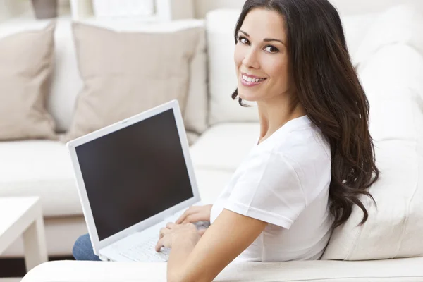 Joven morena mujer usando ordenador portátil en casa en sofá —  Fotos de Stock