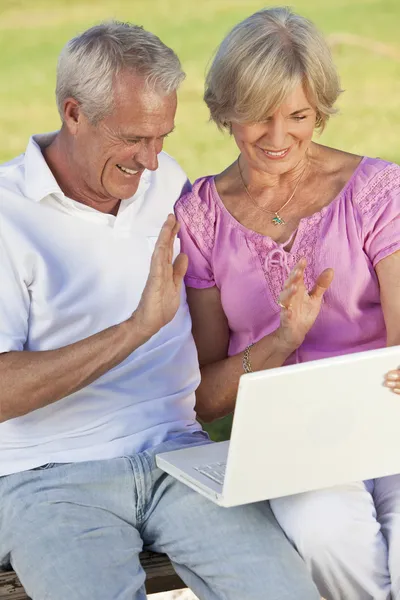 Lyckliga äldre paret använder bärbar dator utanför i solen — Stockfoto