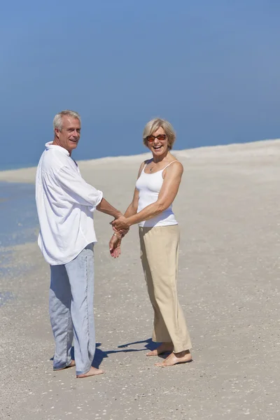 Feliz casal sênior andando segurando as mãos na praia — Fotografia de Stock