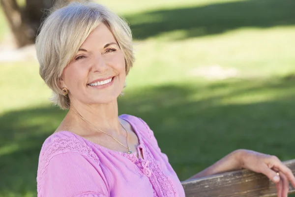 Glückliche Seniorin sitzt draußen und lächelt — Stockfoto