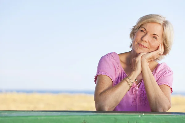 Tankeväckande attraktiv äldre kvinna sitter utanför vid bord — Stockfoto