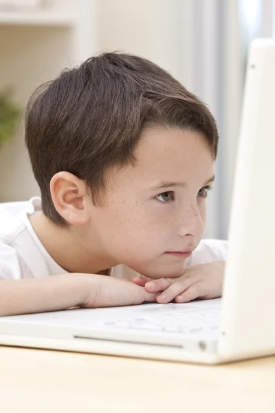 Menino criança usando computador portátil descansando em suas mãos — Fotografia de Stock