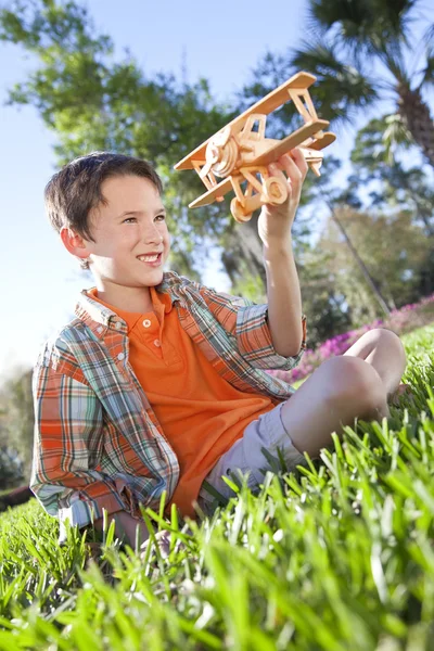 Joven chico fuera jugando con su juguete modelo avión — Foto de Stock