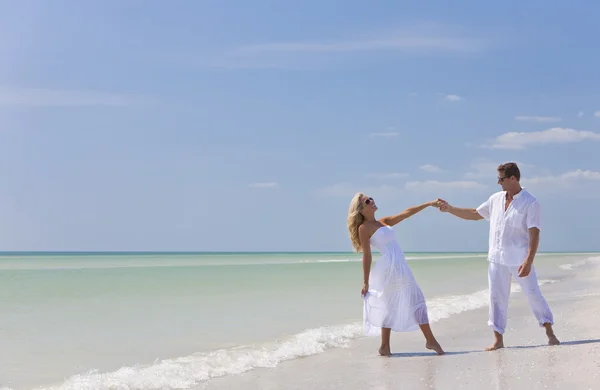 Счастливая молодая пара танцует, держась за руки на пляже — стоковое фото